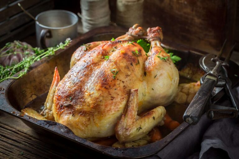 Een goudbruin geroosterde kip, geserveerd op een schotel voor een groepsdiner.